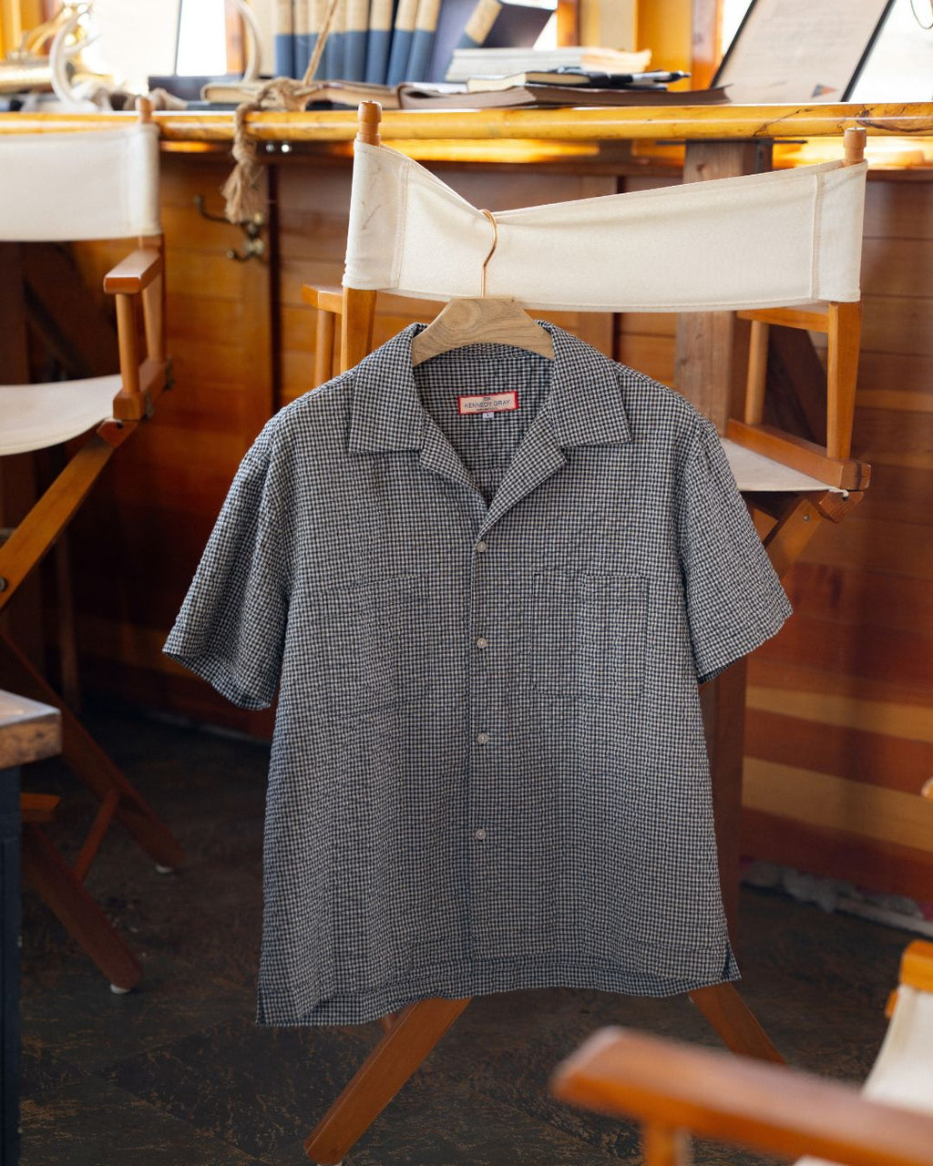 NYC Shirt in blue and white gingham seersucker on a hanger in the saloon of the Robert Gray