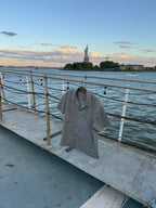 NYC Shirt in blue and white gingham seersucker on a hanger at the rail, Statue of Liberty behind